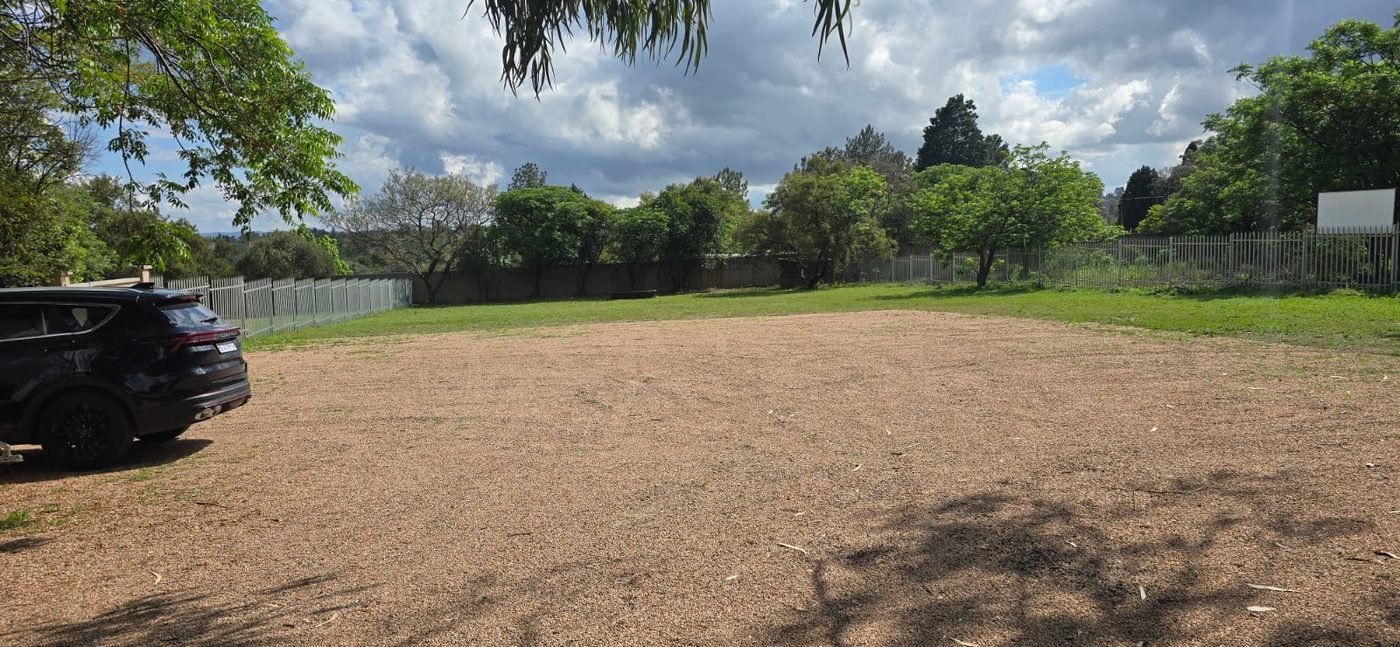 Large gravel parking area shaded by trees